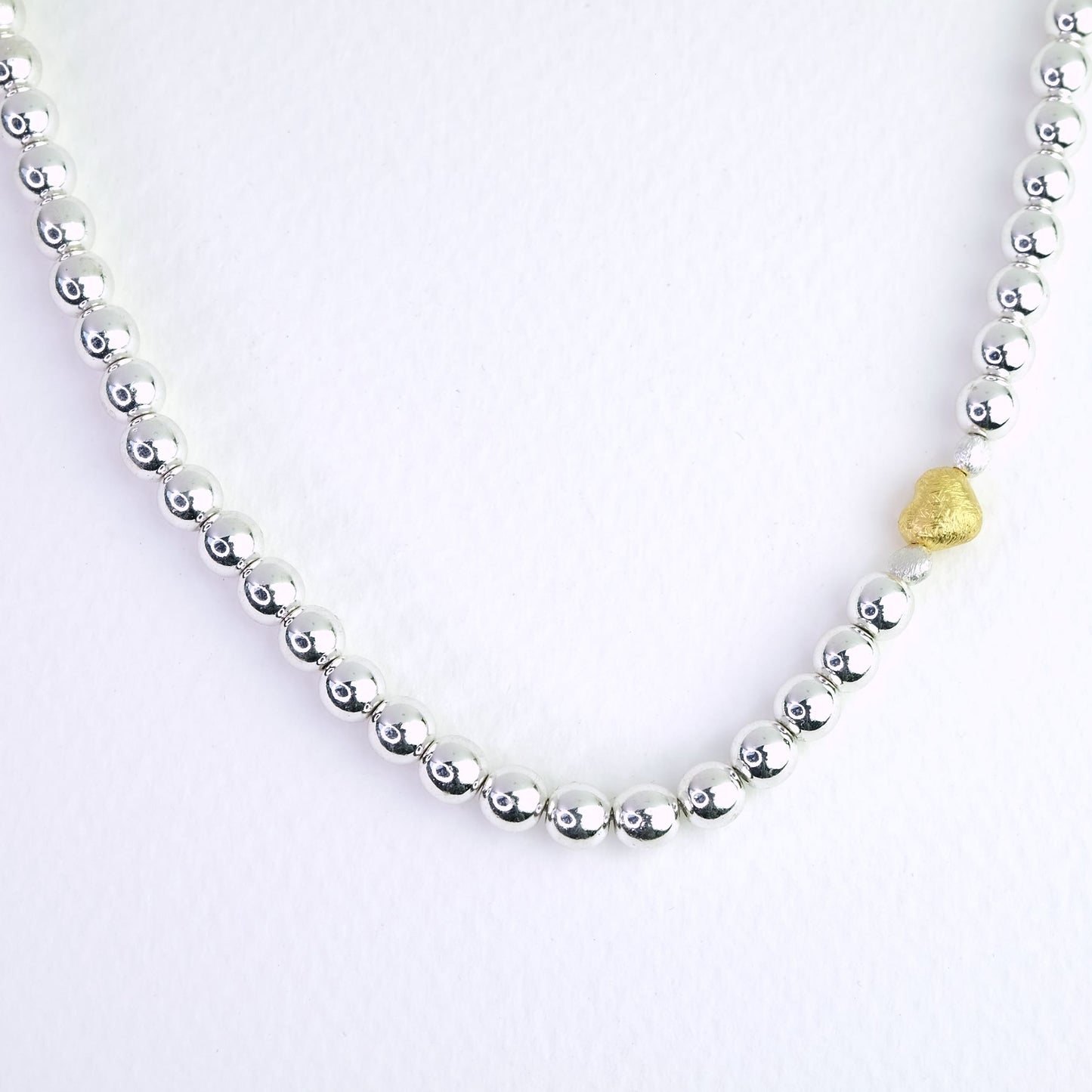 Naszyjnik z kulek hematytowych z dekoracyjnym złotym serduszkiem. Hematite bead necklace with a decorative gold heart.