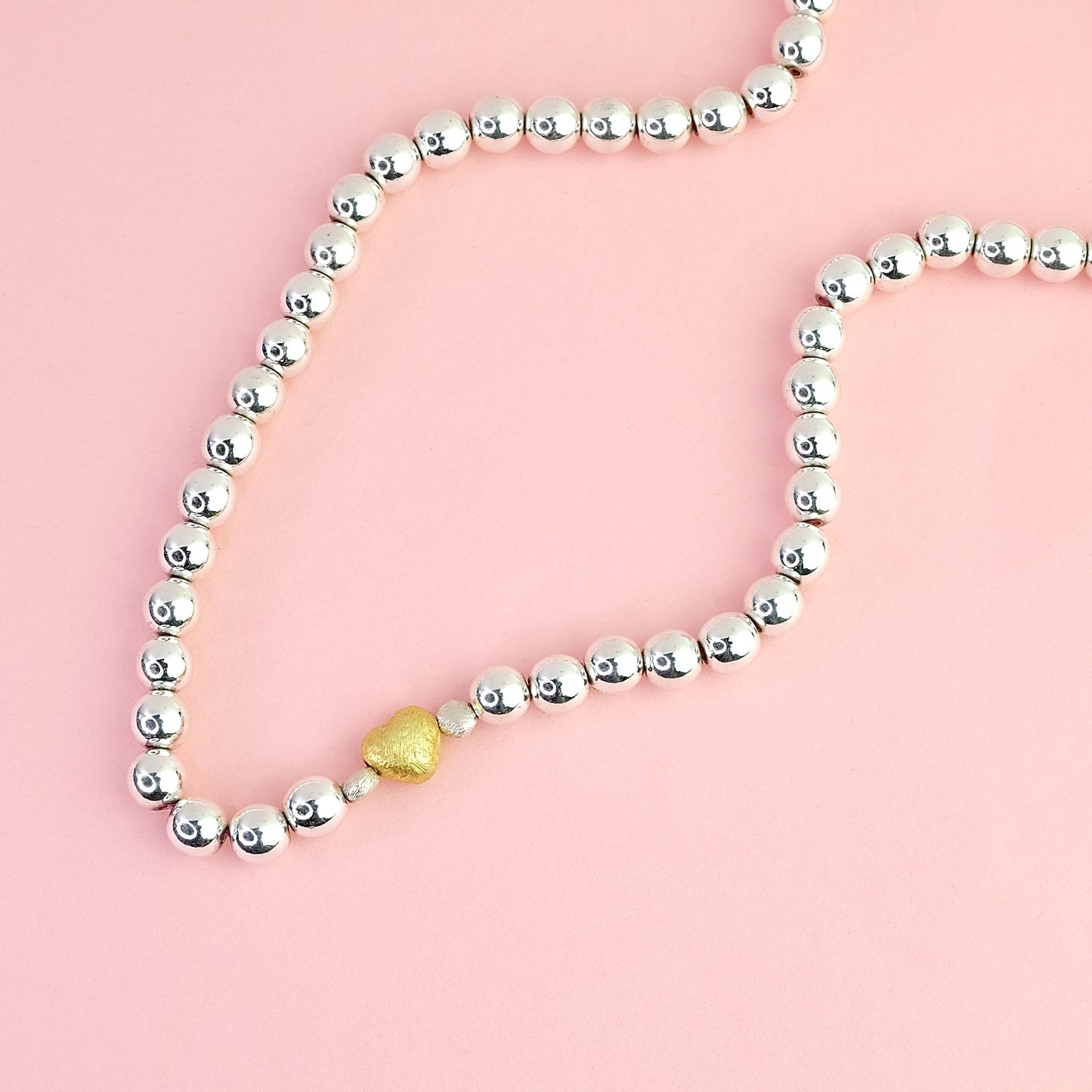Naszyjnik z kulek hematytowych z dekoracyjnym złotym serduszkiem. Hematite bead necklace with a decorative gold heart.