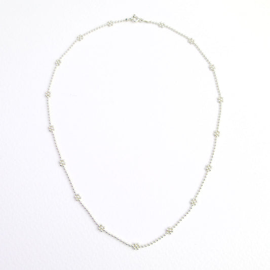 Srebrny łańcuszek z kuleczek z drobnymi kwiatkami.