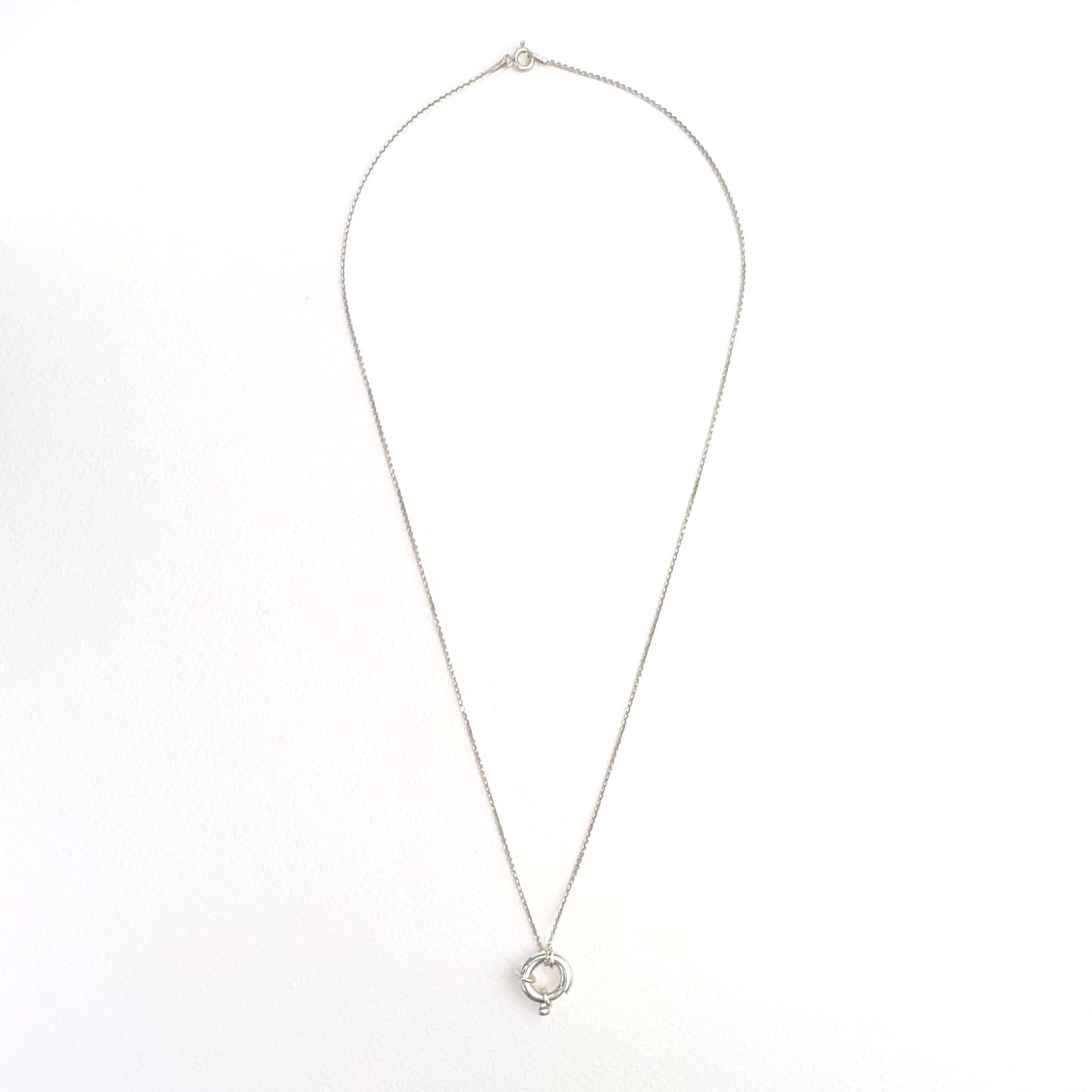 Srebrny naszyjnik z kółkiem federing na jasnym tle.